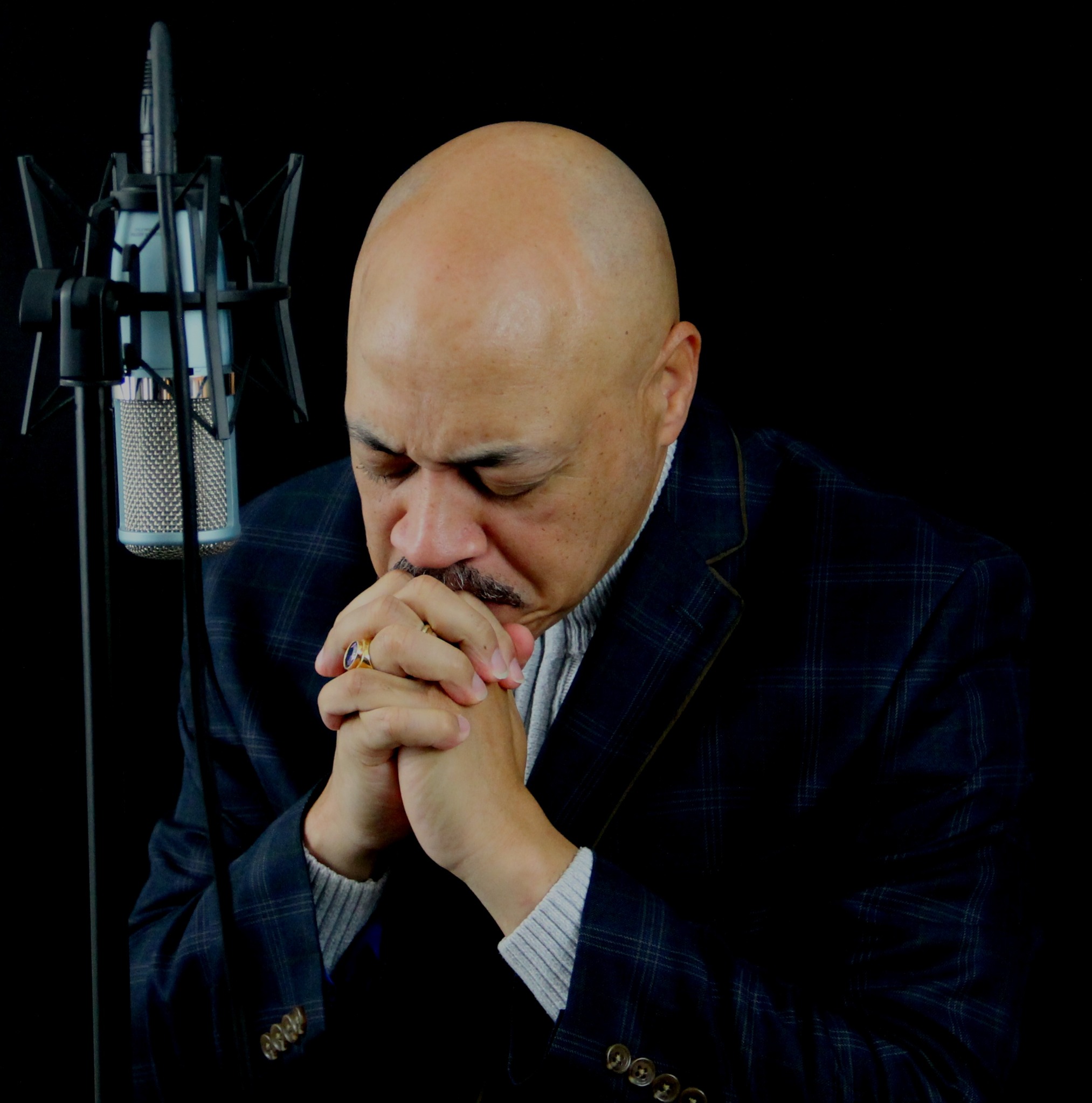 Terry J. Ward praying beside a studio microphone